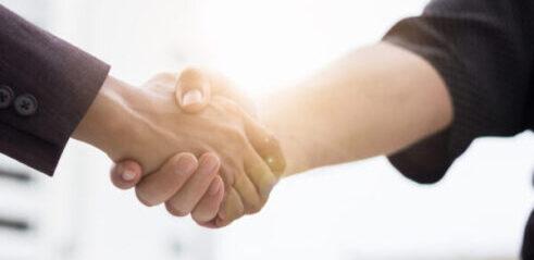 Two businesspeople shake hands to close a deal, thanks to our firm